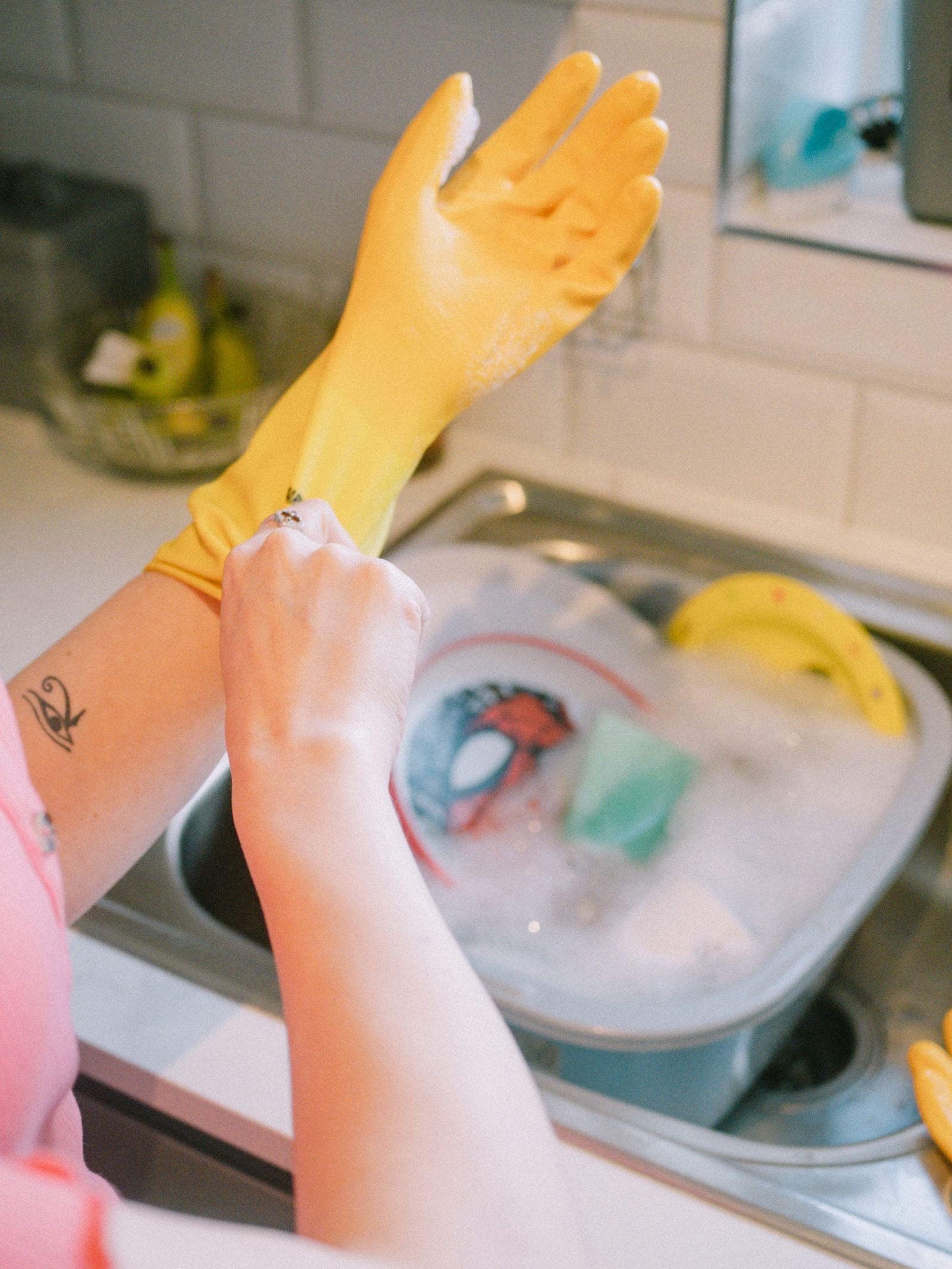 Hands cleaning dishes with gloves for clean first home routine